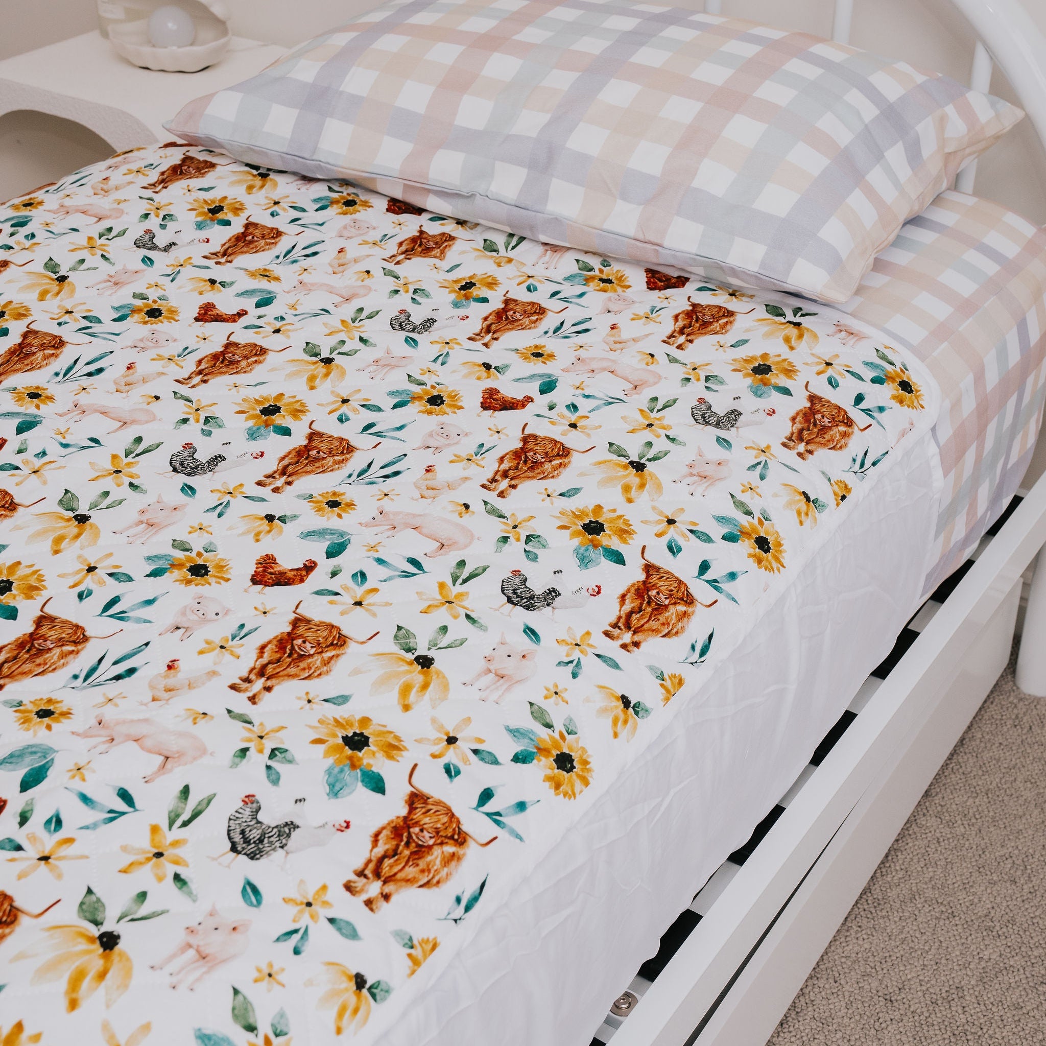 Bed with floral bedding and checkered pillow on a plain background