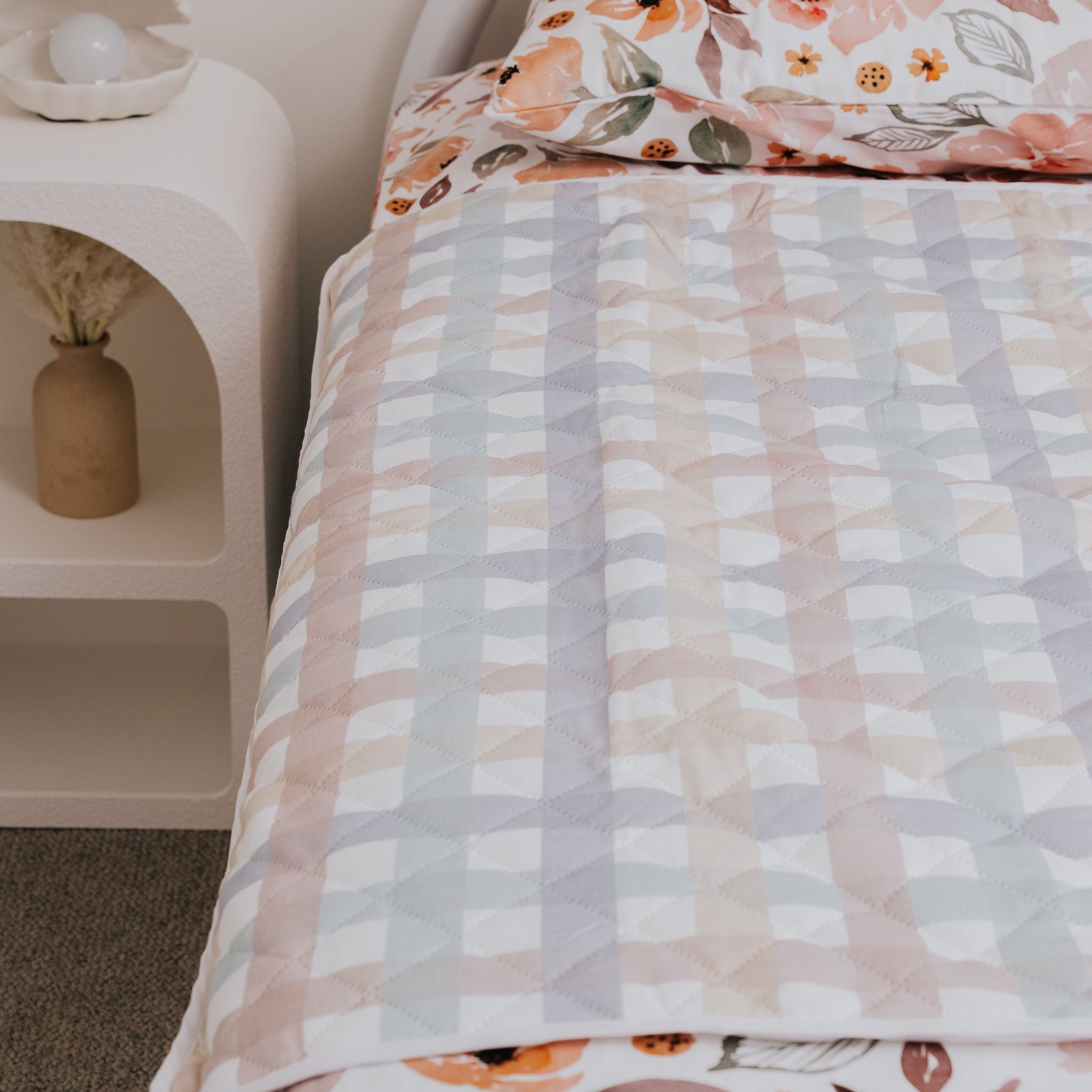 Bed with floral bedding and a nightstand in a bedroom setting