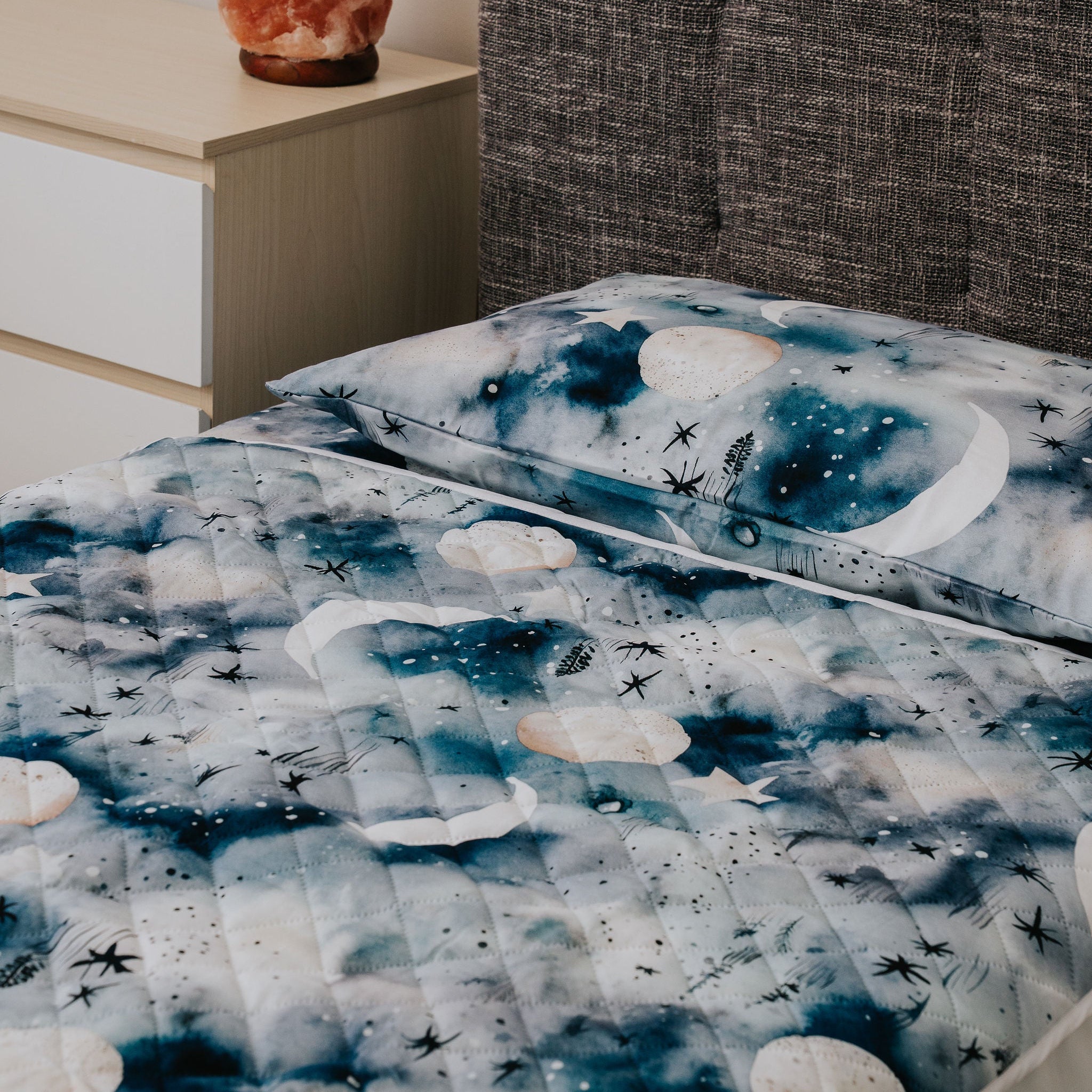 Bed with blue and white patterned comforter in a bedroom setting.