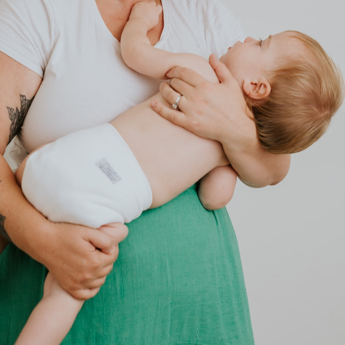 Mum cradling her baby to sleep wearing a cloth nappy