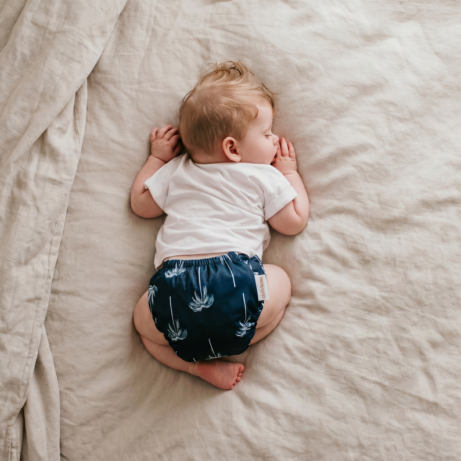 Sleeping baby wearing a Cloth Bums reusable Knight nappy