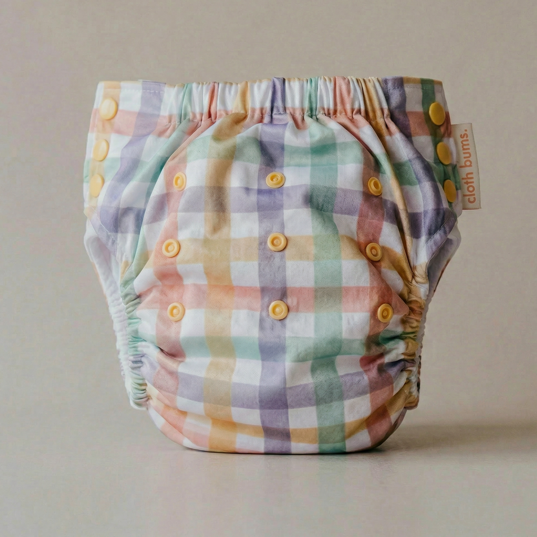 Plaid baby diaper with yellow buttons on a neutral background