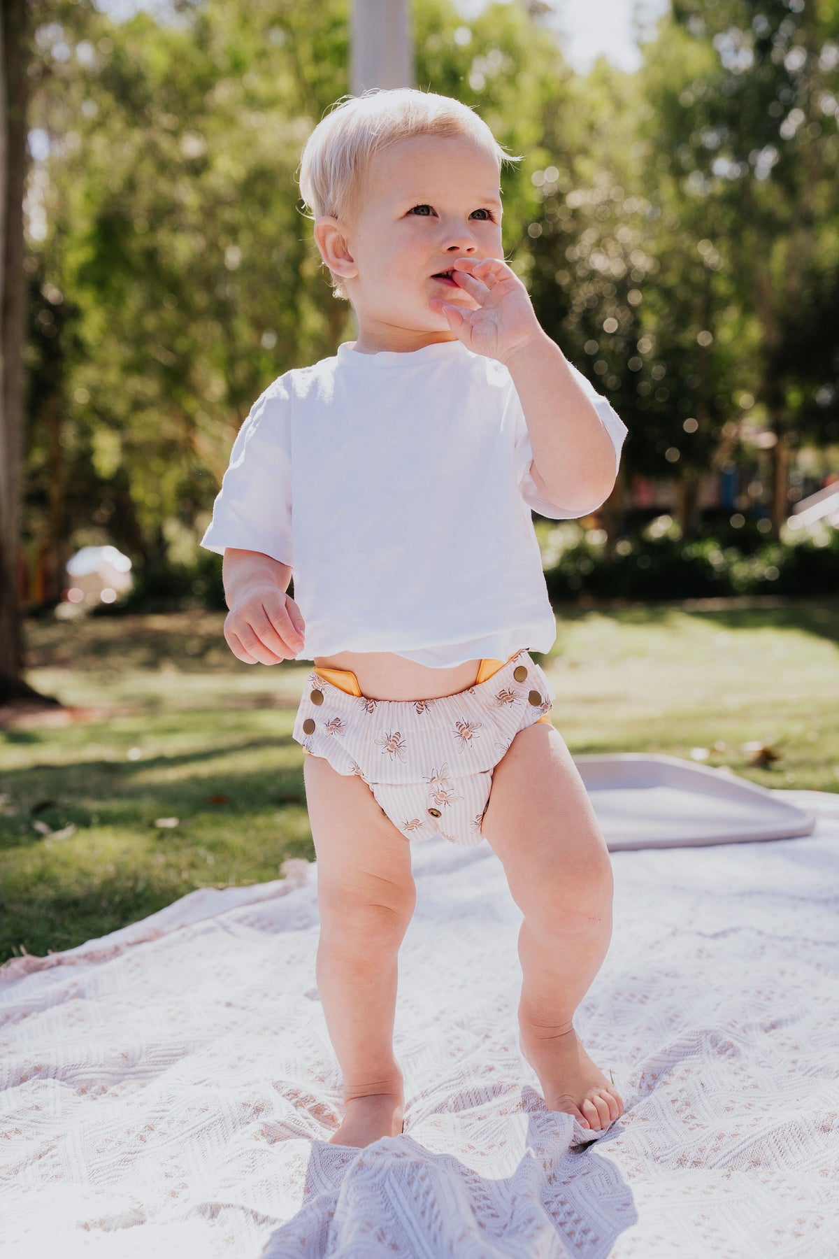 Toddler standing on a picnic rug wearing a Gremlin pull up nappy in Beeline print