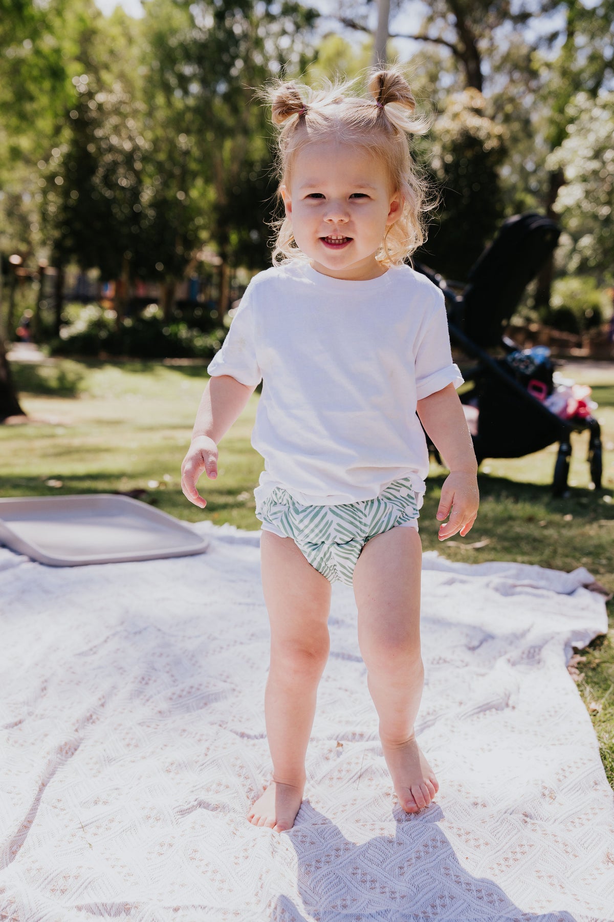 Toddler standing on a picnic blanket wearing a Gremlin pull up nappy in Greenhouse print