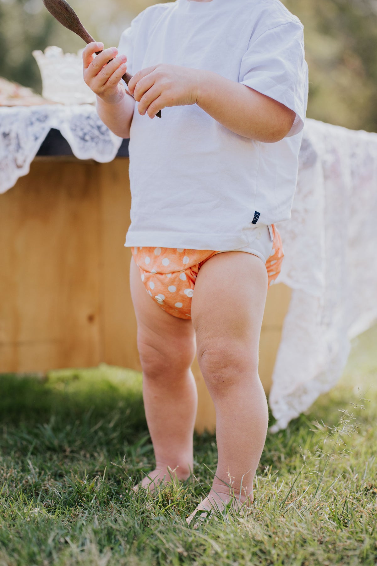 Toddler standing on the grass wearing a Gremlin pull up nappy in Marmalade print