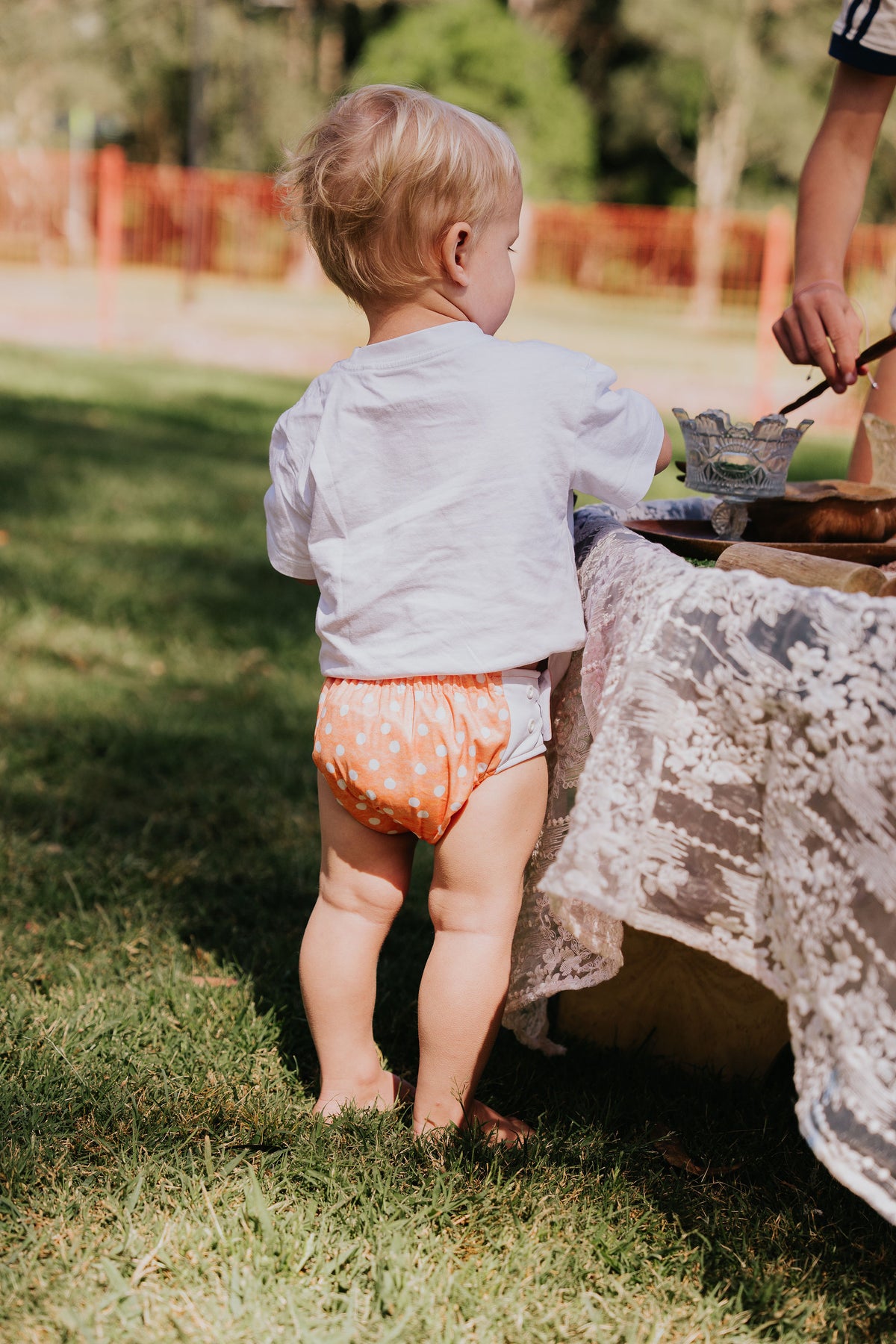 Toddler standing on the grass wearing a Gremlin pull up nappy in Marmalade print