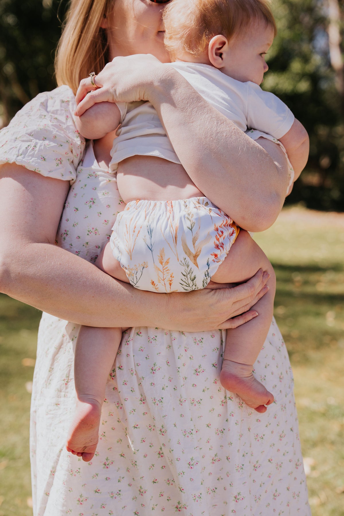 Mum holding her baby, who is wearing a Pixie cloth nappy in Wild Prairie print