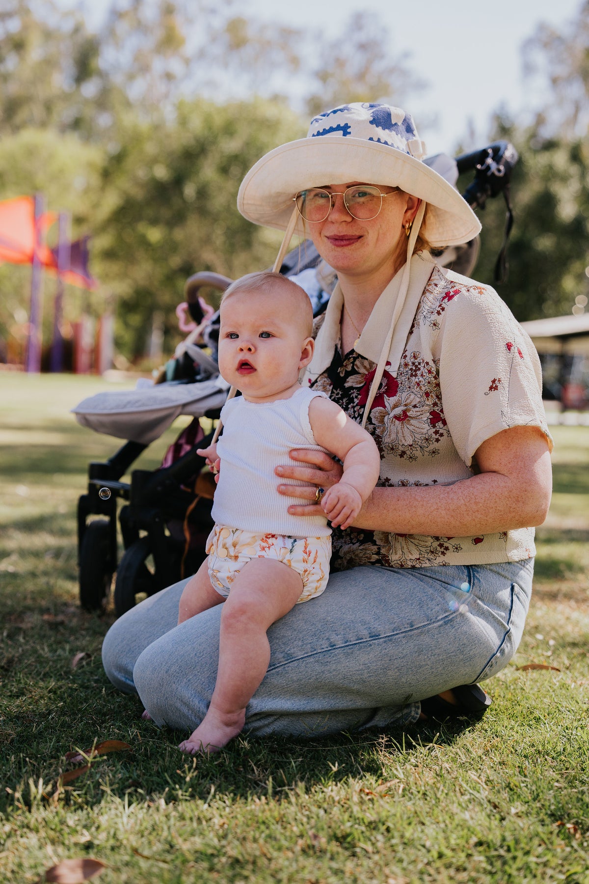Baby sitting on mum's knee outdoors wearing a Pixie cloth nappy in Wild Prairie print