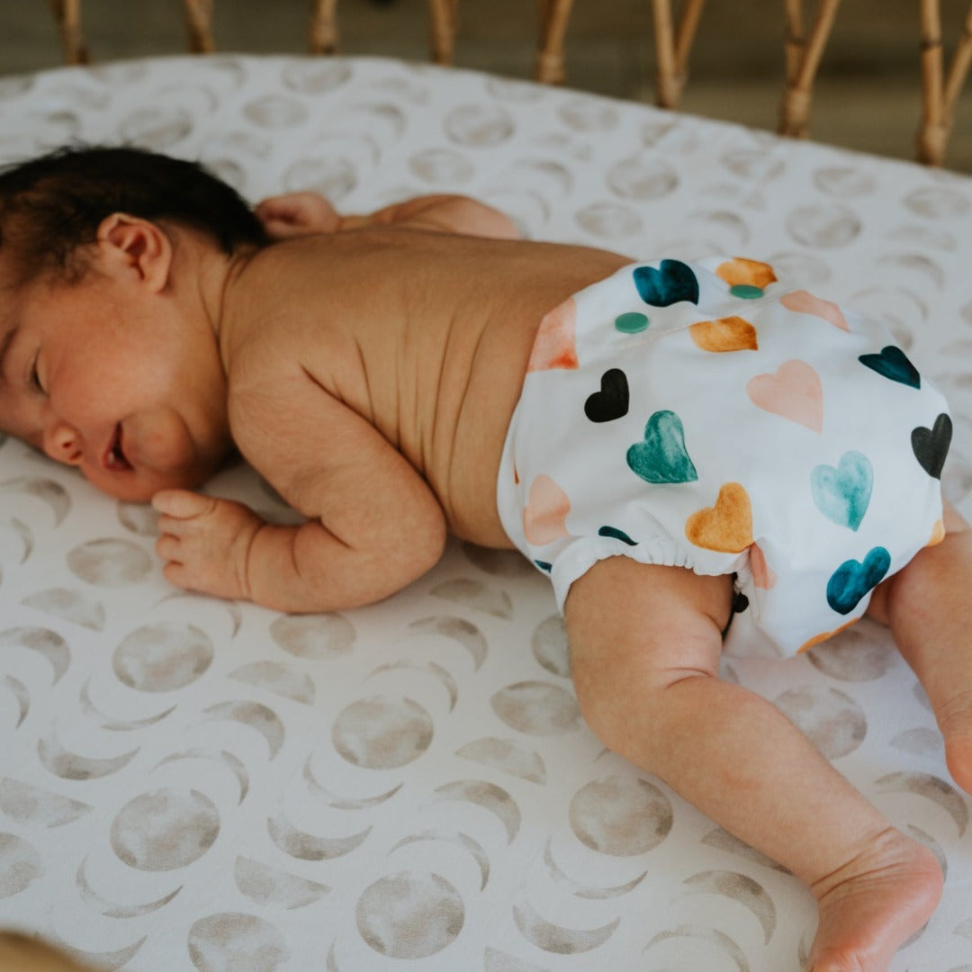 Newborn baby laying on their tummy wearing a reusable cloth nappy