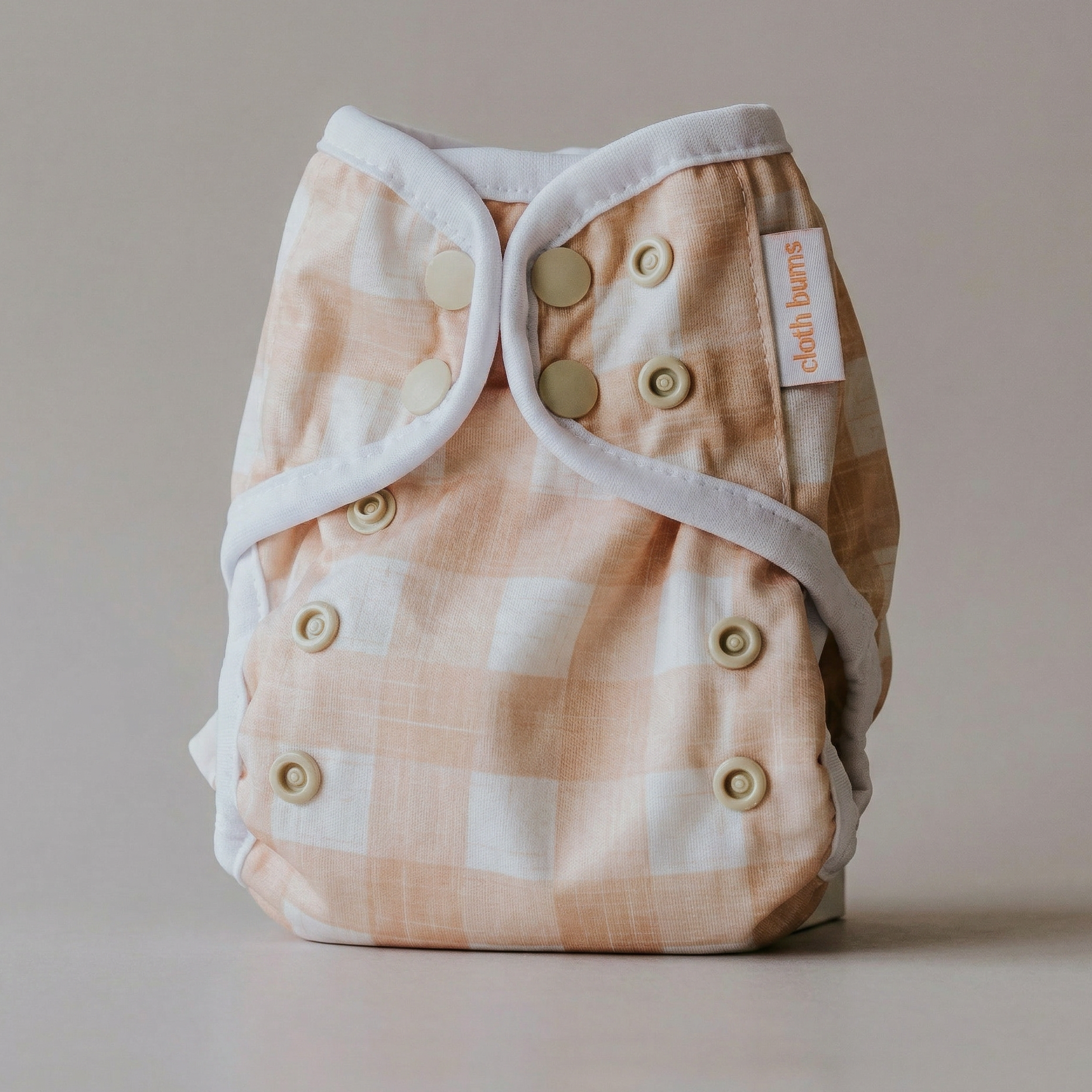 Checkered cloth diaper with button closure on a neutral background