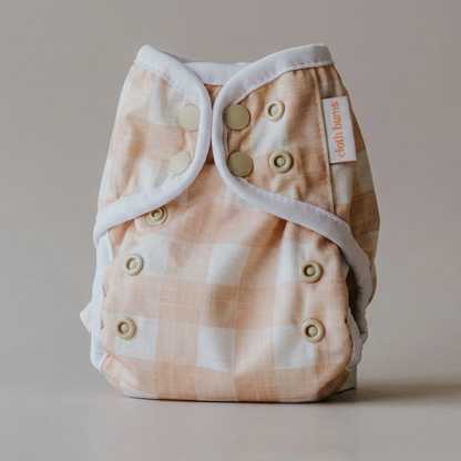 Checkered cloth diaper with button closure on a neutral background
