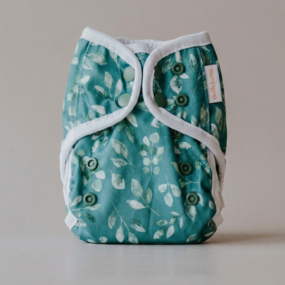 Teal cloth diaper with white leaf pattern on a neutral background