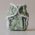 Green cloth diaper with white patterns on a beige background
