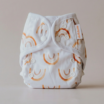 White diaper with orange rainbows and a visible brand tag on a beige background