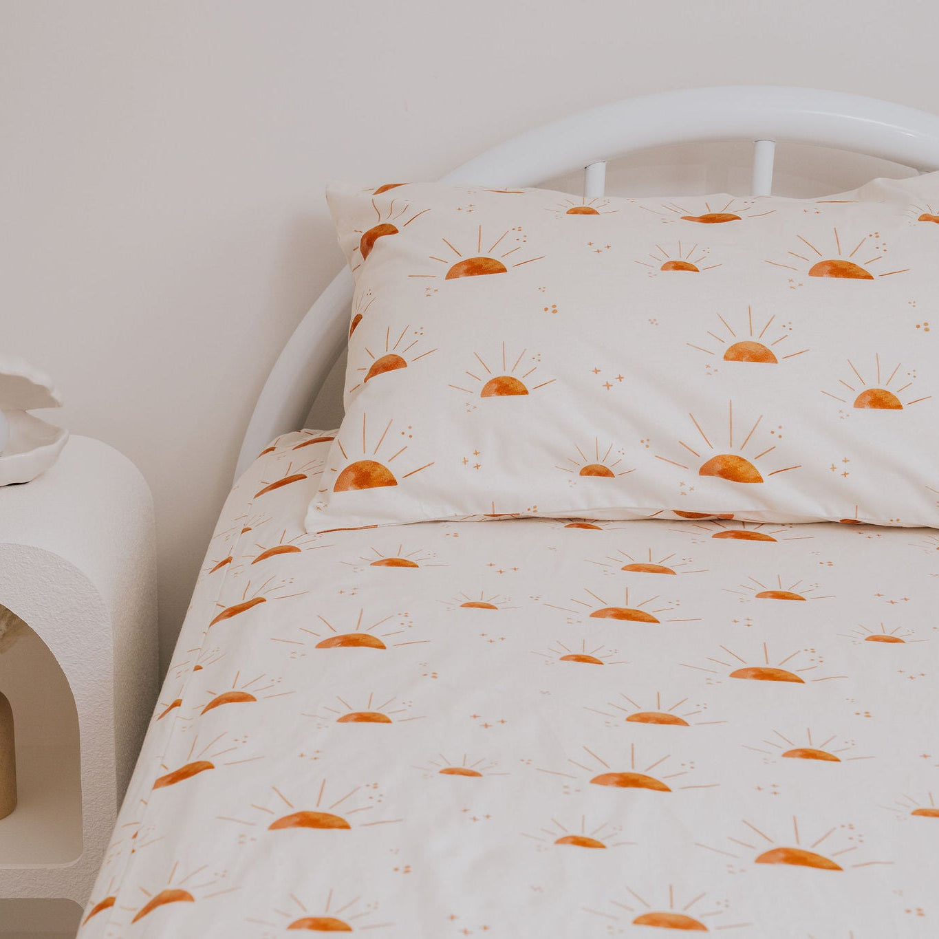 Bed with orange and white patterned bedding in a minimalistic bedroom.