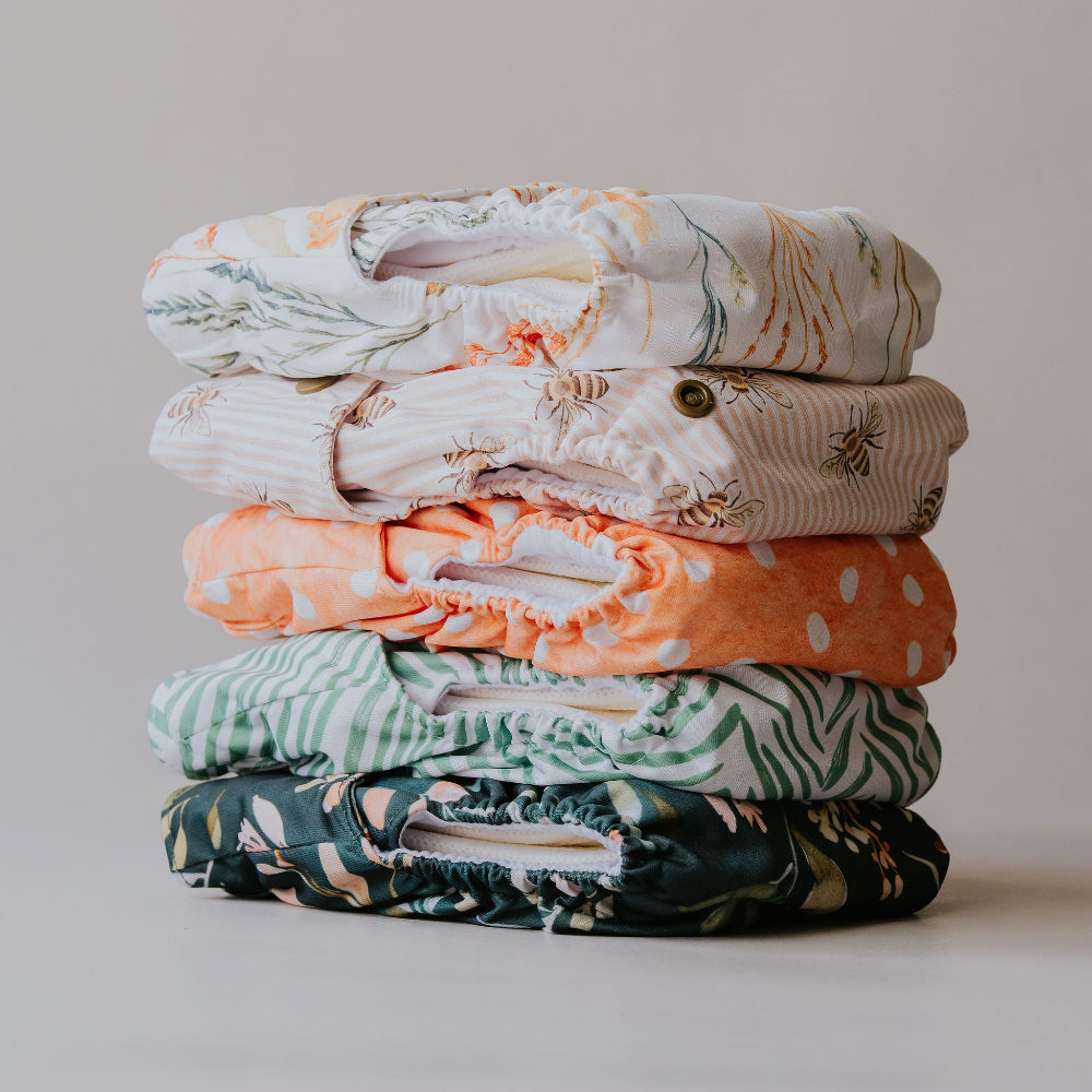 Stack of PIXIE one size cloth nappies in the five new prints, side view
