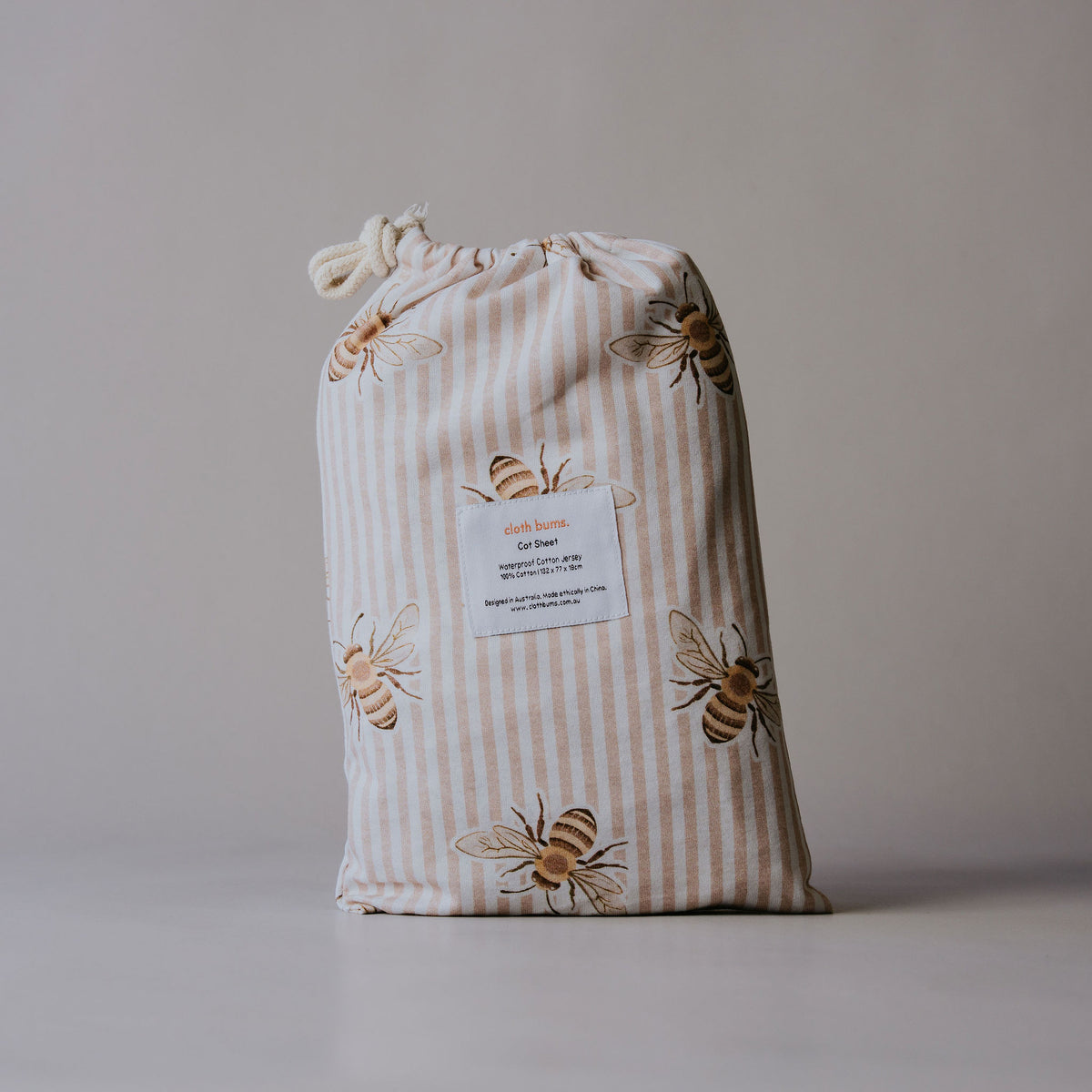 Waterproof cot sheet in Beeline print, packed in its drawstring bag