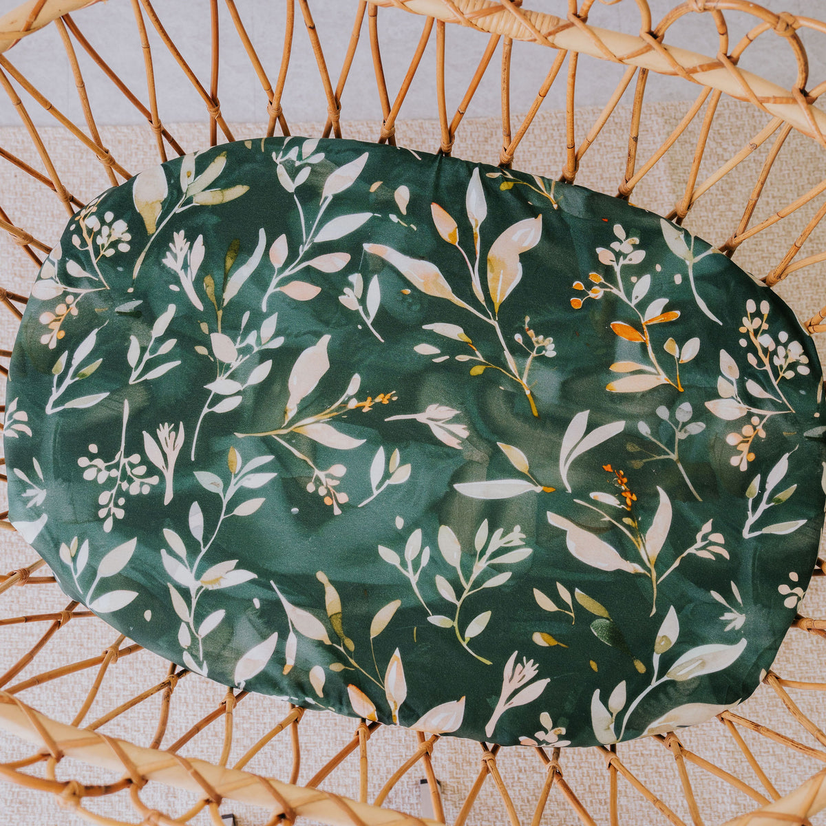 Evergreen waterproof sheet fitted in a rattan bassinet, seen from above
