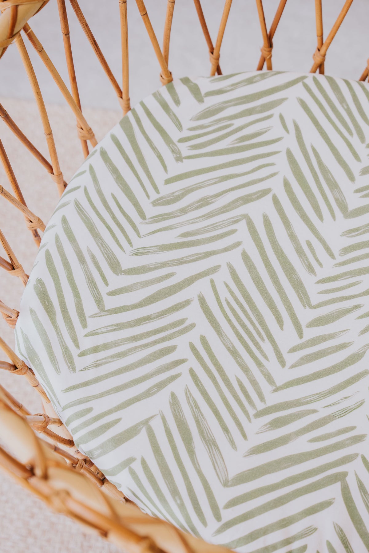 Close-up of the Greenhouse waterproof sheet in a rattan bassinet
