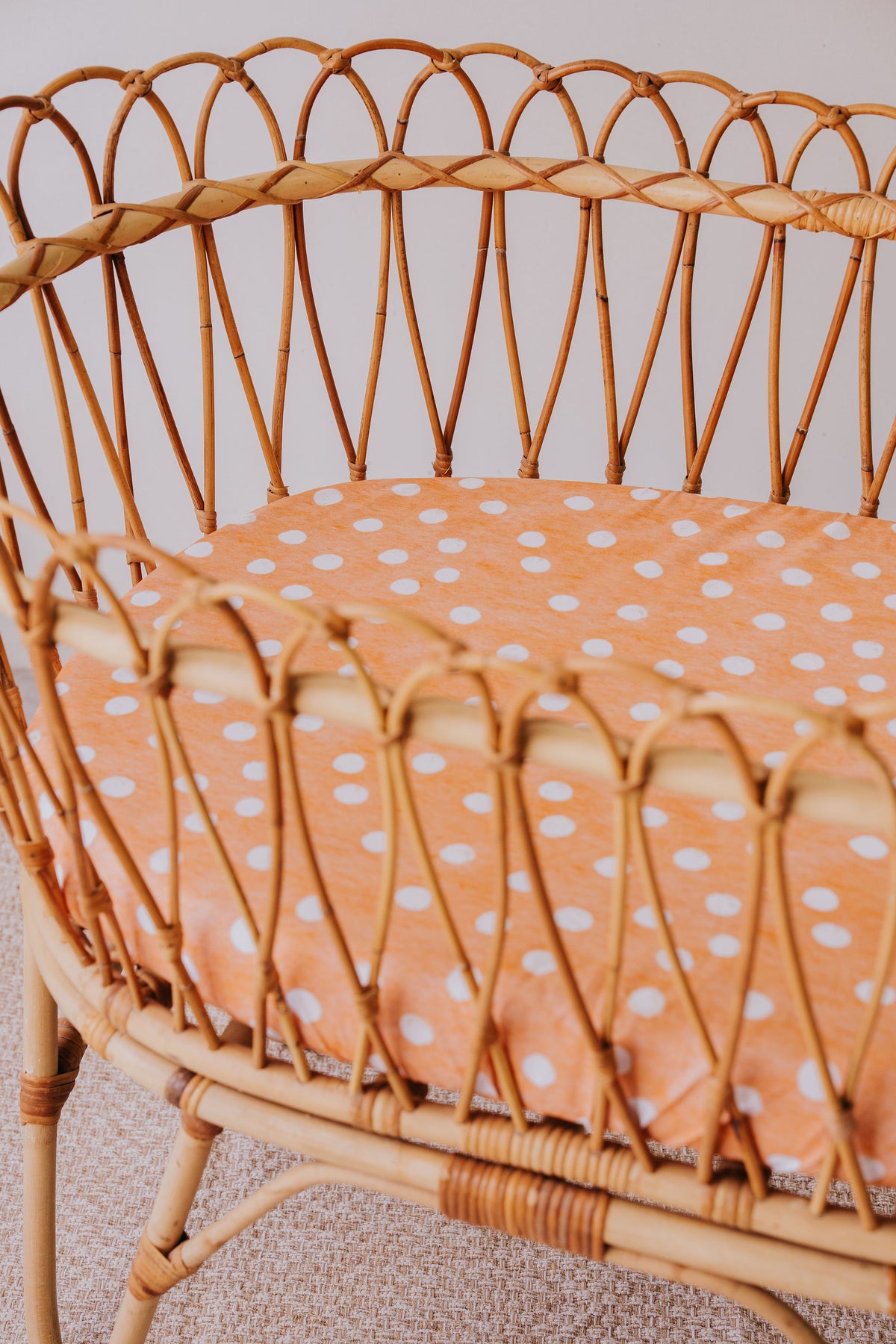 Close-up of the Marmalade waterproof sheet in a rattan bassinet