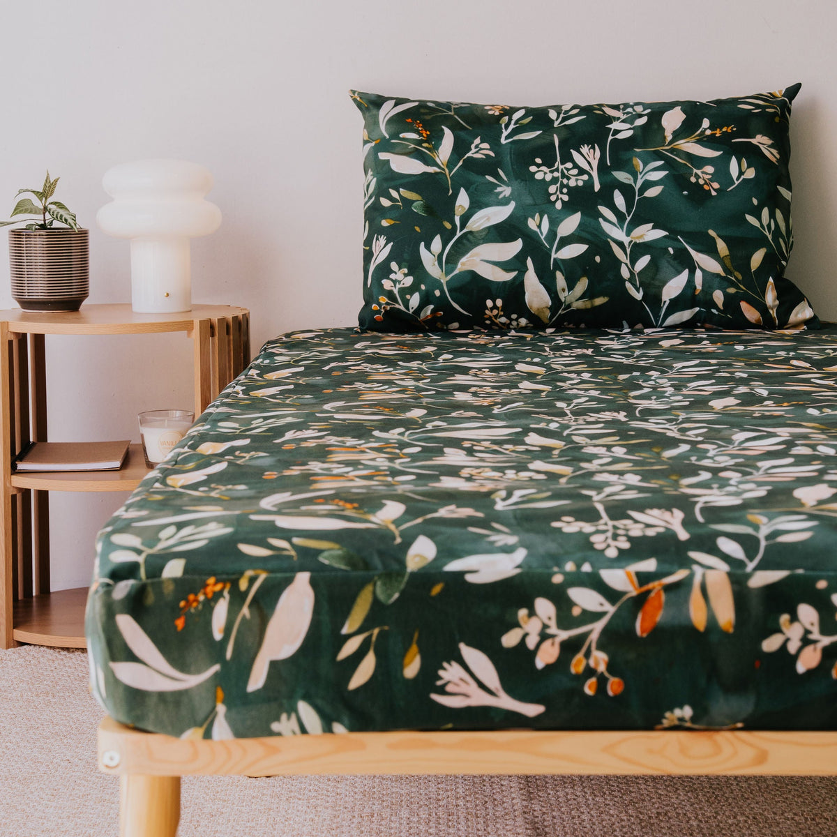 Evergreen waterproof fitted sheet and pillowcase on a bed beside a timber side table