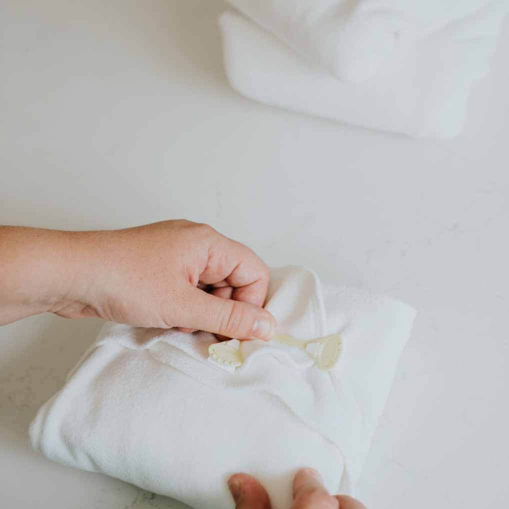 A snappi nappy fastner attaching to a white preflat cloth nappy