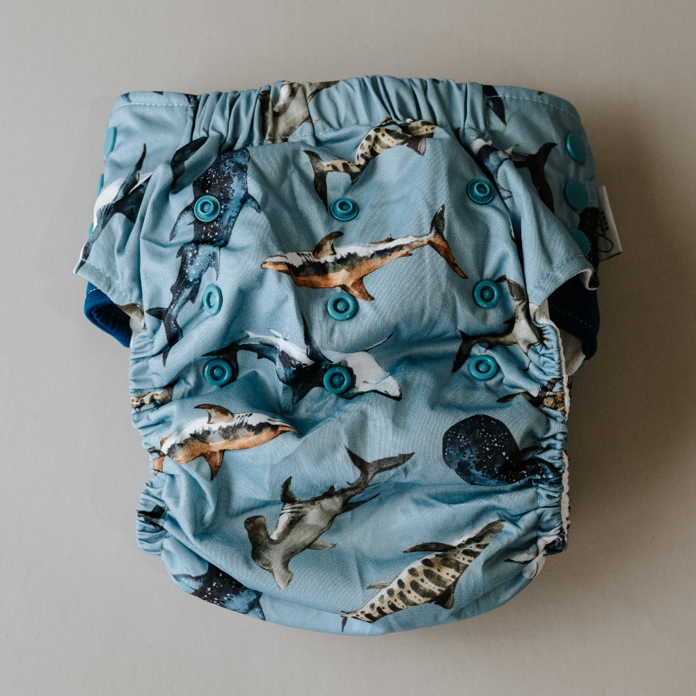 Blue cloth diaper with shark pattern on a beige background