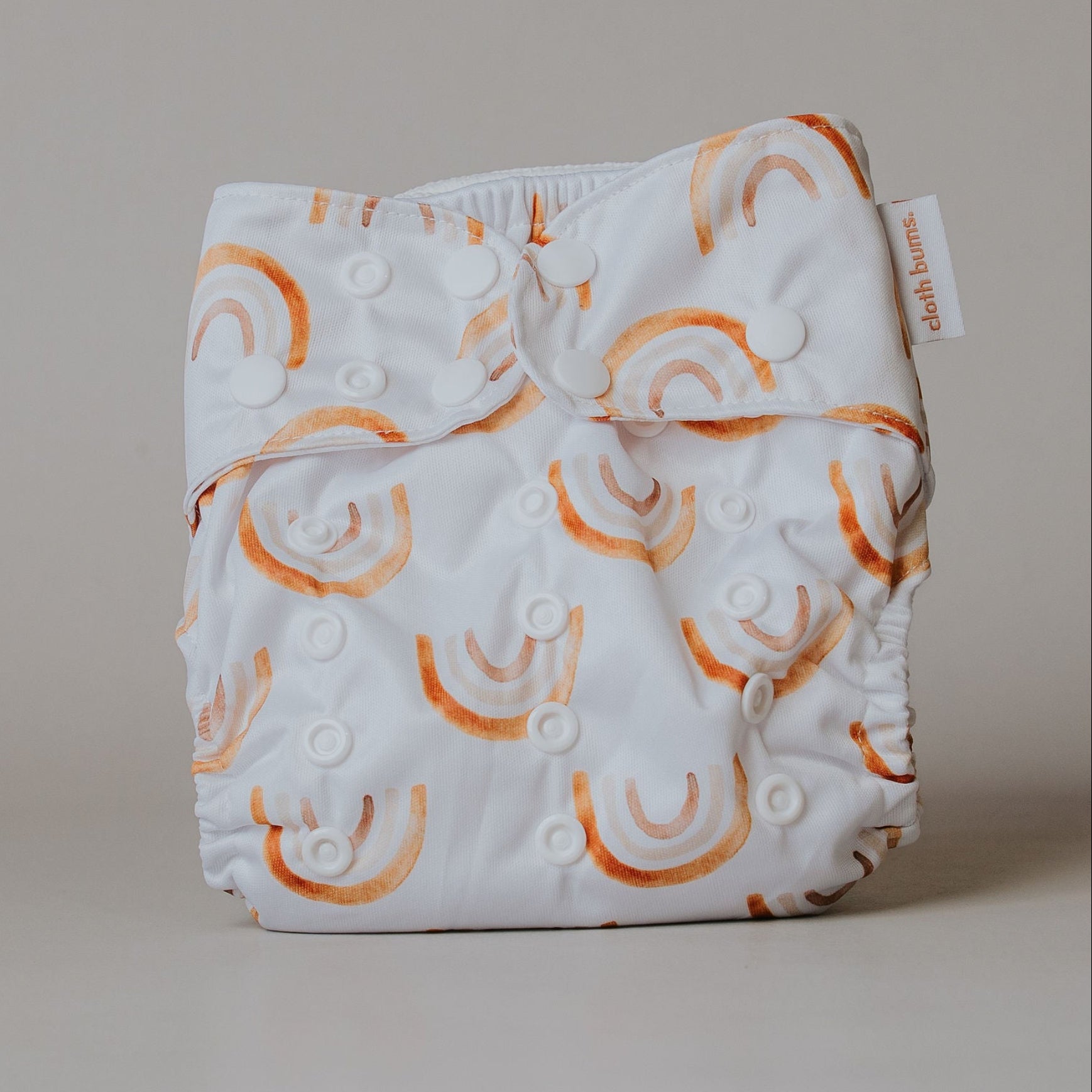 White cloth diaper with orange rainbow patterns on a beige background