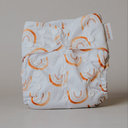 White cloth diaper with orange rainbow patterns on a beige background