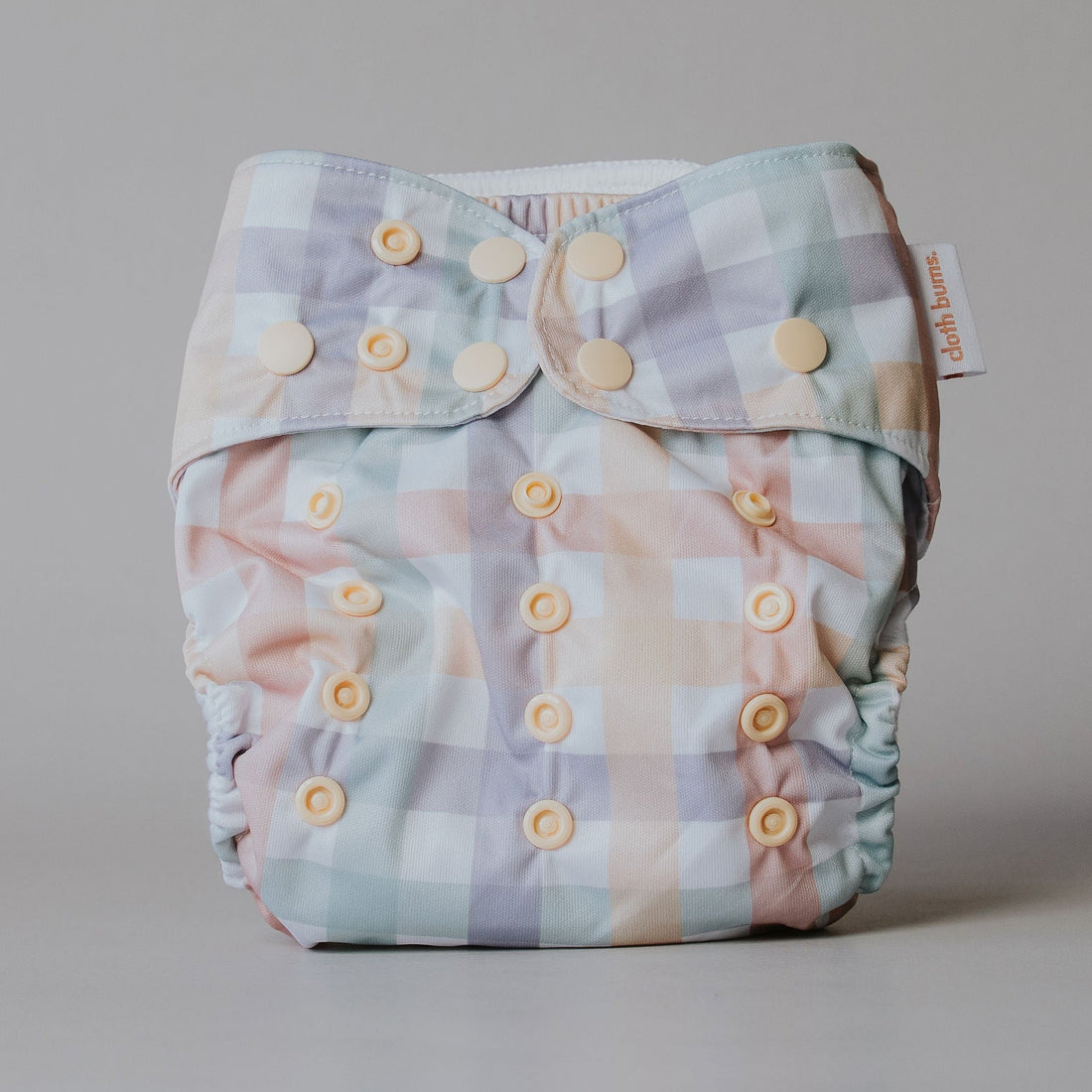 Plaid patterned diaper with button closure on a neutral background